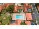 A refreshing community pool surrounded by lounge chairs, palm trees, and tiled roofs in an aerial view at 5015 Nassau Cir # 4, Orlando, FL 32808