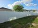 Backyard showcasing well-maintained white fencing and a green lawn with a tree providing shade at 585 Lucerne Blvd, Winter Haven, FL 33881