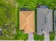 Aerial view of a house with a tile roof, landscaped yard, and a neighboring house with solar panels at 605 San Augusto Dr, Kissimmee, FL 34759
