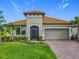 Charming single-story home featuring a tile roof, two-car garage, and lush landscaping with palm trees at 605 San Augusto Dr, Kissimmee, FL 34759