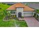 Charming single-story home featuring a tile roof, two-car garage, and lush landscaping with palm trees at 605 San Augusto Dr, Kissimmee, FL 34759