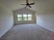 Carpeted main bedroom with a ceiling fan and large windows for natural light at 1069 Pavia Dr, Apopka, FL 32703