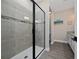 This bathroom features a tiled walk-in shower with glass door, gray wood-style floors, and neutral colored walls at 1335 Greenfield Loop, Kissimmee, FL 34747