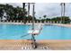 Large community pool with chair lift and ample lounge seating under palm trees at 1335 Greenfield Loop, Kissimmee, FL 34747