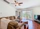 Cozy living room with hardwood floors, a ceiling fan, and sliding glass doors leading to an outdoor patio at 1912 Manatee Ln, Poinciana, FL 34759