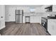 Well-lit kitchen with stainless steel refrigerator, appliances, and white cabinetry and gray wood-look flooring at 2 Dogwood Radl, Ocala, FL 34472