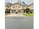 Two-story tan home with brown trim, attached garage, and well-manicured front lawn at 2031 Balboa Way, Kissimmee, FL 34741
