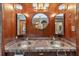 Bathroom featuring dual sinks, a round mirror, and wood-paneled walls at 2225 Maryday Ct, Orlando, FL 32812