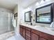 Bright bathroom featuring double vanity with granite countertops, dark wood cabinets, and a glass-enclosed shower at 2939 Sera Bella Way, Kissimmee, FL 34744