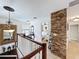 Upstairs hallway with stone accent wall and view into bedroom, featuring lots of natural light at 2939 Sera Bella Way, Kissimmee, FL 34744