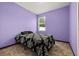 Cozy bedroom with purple walls, natural light from window, and patterned bedspread at 326 Highland Meadows Ave, Davenport, FL 33837