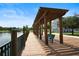 Wooden dock with a pergola and seating overlooking a lake and neighborhood at 4014 Santa Maria Dr # 101, Kissimmee, FL 34741
