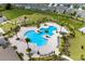 An aerial view of the community pool and playground with seating and palm trees surrounded by houses at 4492 Bluff Oak Loop, Kissimmee, FL 34746