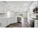 A modern open-concept kitchen features white cabinets, quartz countertops, and stainless steel appliances at 4613 Madison Ave, Lake Wales, FL 33859
