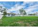 View of the spacious backyard with lush green grass, and the house exterior with an open porch at 4615 Madison Ave, Lake Wales, FL 33859