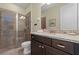 Bathroom with tiled shower, granite counters, dark wood cabinets and decorative art at 551 Lasso Dr, Kissimmee, FL 34747