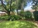 Green backyard with a chain-link fence, grass, and landscaping that includes a variety of trees and plants at 6478 Inca St, Orlando, FL 32807