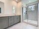 Bathroom featuring double vanity with gray cabinets, quartz countertop, and glass shower at 7685 Stone Creek Trl, Kissimmee, FL 34747