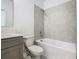 Well-lit bathroom featuring gray vanity, toilet and shower-tub with gray tiling at 7685 Stone Creek Trl, Kissimmee, FL 34747