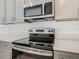 Close-up view of the stainless steel oven and microwave against the backdrop of grey cabinets at 7685 Stone Creek Trl, Kissimmee, FL 34747