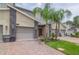 Attractive townhome featuring a two-car garage, brick driveway, and lush tropical landscaping at 783 Ocean Course Ave, Davenport, FL 33896