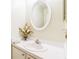 Bathroom featuring white vanity, oval mirror, and a decorative flower arrangement at 7922 Elmstone Cir, Orlando, FL 32822