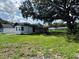 Spacious backyard featuring a small covered patio and a mature tree providing ample shade at 793 N Kentucky Ave, Umatilla, FL 32784