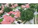An aerial view shows many houses with red roofs and a black car in the driveway, surrounded by trees at 8057 Marcella Dr, Orlando, FL 32836