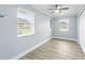 Clean bedroom with wood-look tile flooring, two windows, and a ceiling fan at 911 Mendoza Ln, Kissimmee, FL 34758