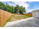 A fenced backyard featuring a concrete slab, grassy area, and beautiful trees at 1009 S Ivey Ln, Orlando, FL 32811