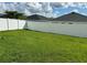 View of the well-maintained green lawn, enclosed by a white fence, of this back yard at 1016 Cascade Dr, Davenport, FL 33837