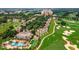 Beautiful aerial view of townhomes, a golf course, and a community pool with mature palm trees at 1592 Heritage Crossing Ct # 202, Reunion, FL 34747