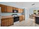 Functional kitchen with wood cabinets, appliances, tile floor, and a view of the dining area with natural light at 1760 Saint Tropez Ct, Kissimmee, FL 34744