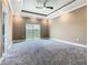 Bright primary bedroom features a tray ceiling, carpet and private balcony access at 1870 Brentwood Ct, Davenport, FL 33837