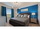 Stylish bedroom with a plush bed, blue accent wall, modern lighting, and a large window at 2176 Lelani Cir, Davenport, FL 33897