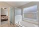 Bright bathroom with a separate tub and shower featuring white tile and frosted windows for natural light at 2685 Oneida Loop, Kissimmee, FL 34747