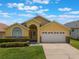 Charming yellow single Gathering home featuring a two-car garage, well maintained lawn, and manicured landscaping at 2685 Oneida Loop, Kissimmee, FL 34747
