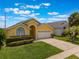 Beautiful yellow single Gathering home with two car garage, arched entryway, and green lawn at 2685 Oneida Loop, Kissimmee, FL 34747