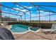 Screened-in pool area has brick patio with a hot tub, lawn chairs and lush green landscaping at 2685 Oneida Loop, Kissimmee, FL 34747