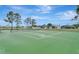 Well-maintained tennis court with green surface, surrounded by trees and a fence for recreational play at 2685 Oneida Loop, Kissimmee, FL 34747