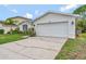 Home exterior showcasing a two-car garage, manicured lawn, and mature landscaping under a bright blue sky at 307 Balmoral Ct, Davenport, FL 33896