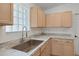 Well-lit kitchen featuring a stainless steel sink, light wood cabinets, and marble-style countertops at 307 Balmoral Ct, Davenport, FL 33896
