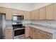 Modern kitchen with stainless steel appliances, light wood cabinets, and marble-style countertops at 307 Balmoral Ct, Davenport, FL 33896