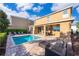 Backyard oasis with a sparkling pool, brick patio, covered seating area, and lush greenery for ultimate relaxation at 321 Lasso Dr, Kissimmee, FL 34747