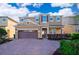 Charming two-story home with a two-car garage, brick driveway, and beautifully landscaped front yard under sunny skies at 321 Lasso Dr, Kissimmee, FL 34747