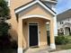Exterior shot of peach siding, white trim, and a black front door with a welcome mat at 3301 Soho St # 104, Orlando, FL 32835