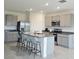 A spacious kitchen featuring grey cabinets, granite countertops, stainless steel appliances, and a large center island with seating at 3886 Whitney Way, Haines City, FL 33844