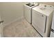 Neat laundry room with white tile floors and modern, matching washer and dryer at 3886 Whitney Way, Haines City, FL 33844