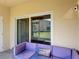 An outdoor patio features a sliding glass door and a comfortable purple couch with beach themed pillow at 4850 Coral Castle Dr, Kissimmee, FL 34746