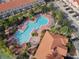 Aerial view of the unique community pool, lounge chairs, landscaping, and nearby buildings at 4850 Coral Castle Dr, Kissimmee, FL 34746